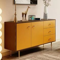 a yellow sideboard with two giraffes on top and a lamp next to it