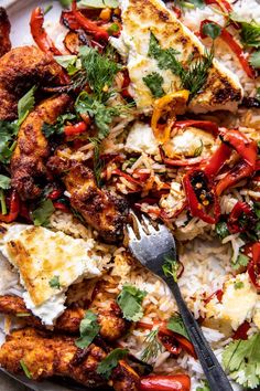 a white plate topped with chicken, rice and veggies next to a fork