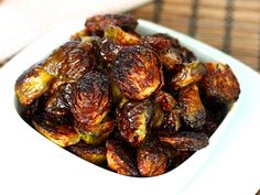 a white bowl filled with roasted brussel sprouts on top of a table