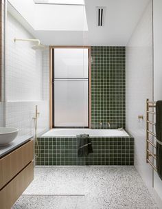 a green tiled bathroom with a skylight above the bathtub and sink area is shown