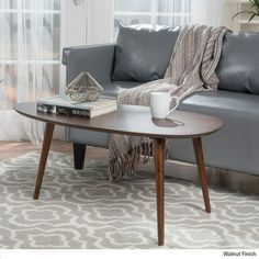 a living room with a gray couch, coffee table and window in the back ground