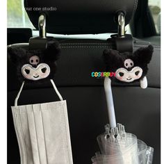 two black and white masks are hanging from the back of a car seat with toothbrushes in it