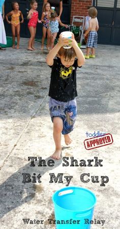 a little boy that is standing in the sand with a bucket and some people behind him