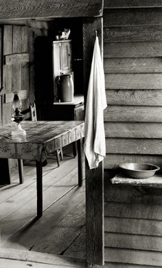 an old photo of a table and chair in a room with wood floors, walls and doors