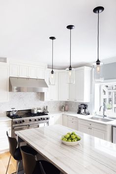 a bowl of green apples sitting on top of a kitchen counter next to an oven