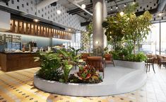 an indoor cafe with plants in the center and tables on either side, along with chairs