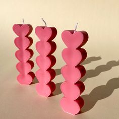 three heart shaped candles sitting on top of a white table next to each other in the shape of hearts