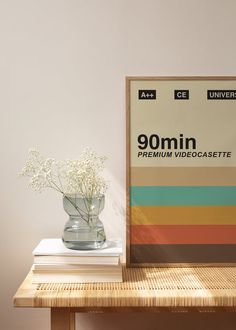 a vase filled with white flowers sitting on top of a table next to a framed poster