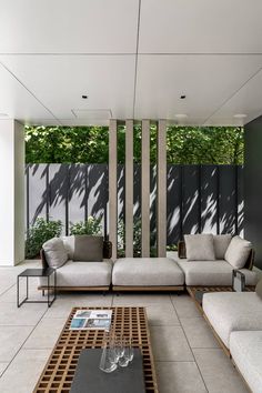 a living room filled with lots of furniture next to tall windows on the side of a building