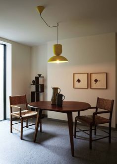 a dining room table with two chairs and a vase on the table next to it