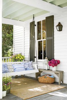 the front porch is decorated with flowers, plants and a bench for sitting on it