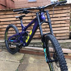 a blue and yellow bike parked in front of a wooden fence