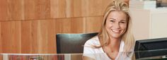 a woman sitting at a desk smiling for the camera