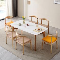 a dining table with four chairs around it and a vase on the table next to it