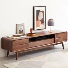 a wooden entertainment center with two lamps on each side and a painting hanging above it