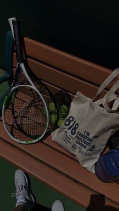 a tennis racket, ball and bag sitting on a bench