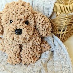 a stuffed dog sitting on top of a blanket next to a wicker basket filled with yarn