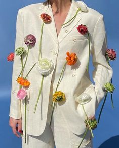 a woman wearing a white suit with flowers on it