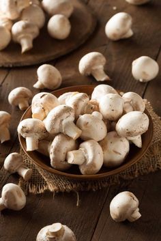 a bowl filled with white mushrooms on top of a wooden table