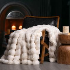 a chair with a blanket on top of it next to a fire place and candles