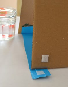 a cardboard box sitting on top of a table next to a glass filled with water