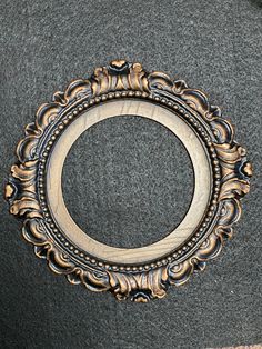 an ornate gold frame on top of a gray carpeted floor with a black background