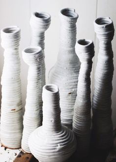 several white vases sitting on top of a wooden table