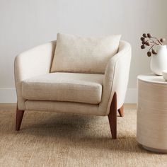 a chair and vase sitting on the floor in front of a wall with white walls