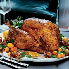 a roasted turkey on a platter with oranges and grapes