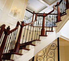 an elegant staircase with wrought iron railings and chandelier on the second floor