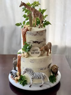 a three tiered cake decorated with animals and plants