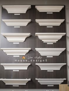 several white shelves on the wall with arabic writing and numbers above them that read house designs