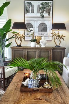 a wooden table topped with lots of plants and vases next to a wall mounted art piece