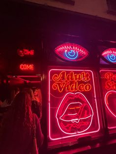 neon signs on the side of a building with people standing around them at night time