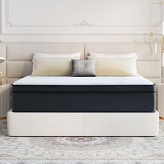 an image of a bed with pillows on it in the middle of a room that is white and beige