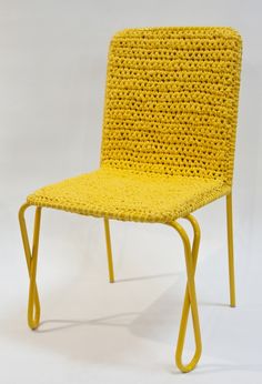 a yellow chair sitting on top of a white floor next to a wooden table with a crocheted seat