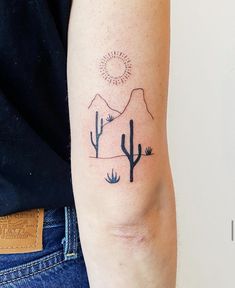 a person with a tattoo on their arm that has cactus and mountains in the background