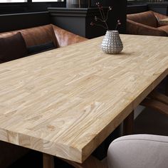 a large wooden table with chairs and a vase on the table in front of it