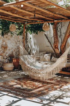 a white hammock sitting on top of a rug under a pergolated roof