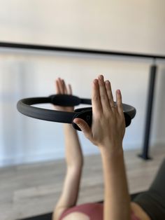 a woman is doing yoga with her hands on the ground and holding onto a black object