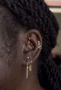 a close up of a person with ear piercings on their ears and hair in the background