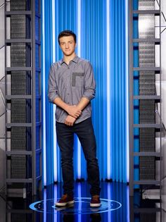 a young man standing in front of a blue and white background with his hands on his hips