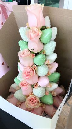 a box filled with pink roses and green candies