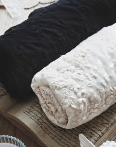 two black and white blankets on top of an open book with paper doily around them