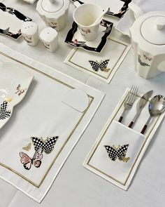 the table is set with black and white butterfly napkins, silverware, and tea cups