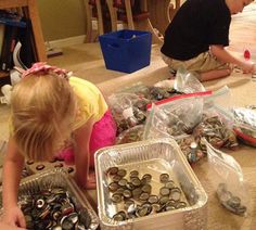 two children are playing with tin cans and other items on the floor in front of them