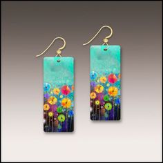 earrings with flowers painted on them are hanging from the earwires in front of a gray background