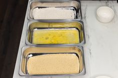 three pans filled with food sitting on top of a counter next to a bowl