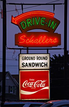 a neon sign that says drive - in saddlers and ground round sandwich with coca cola