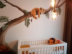 a baby's room with a tree mural on the wall and a crib